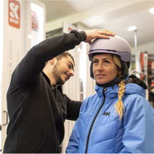 Femme qui loue un casque de ski dans un magasin Skiset